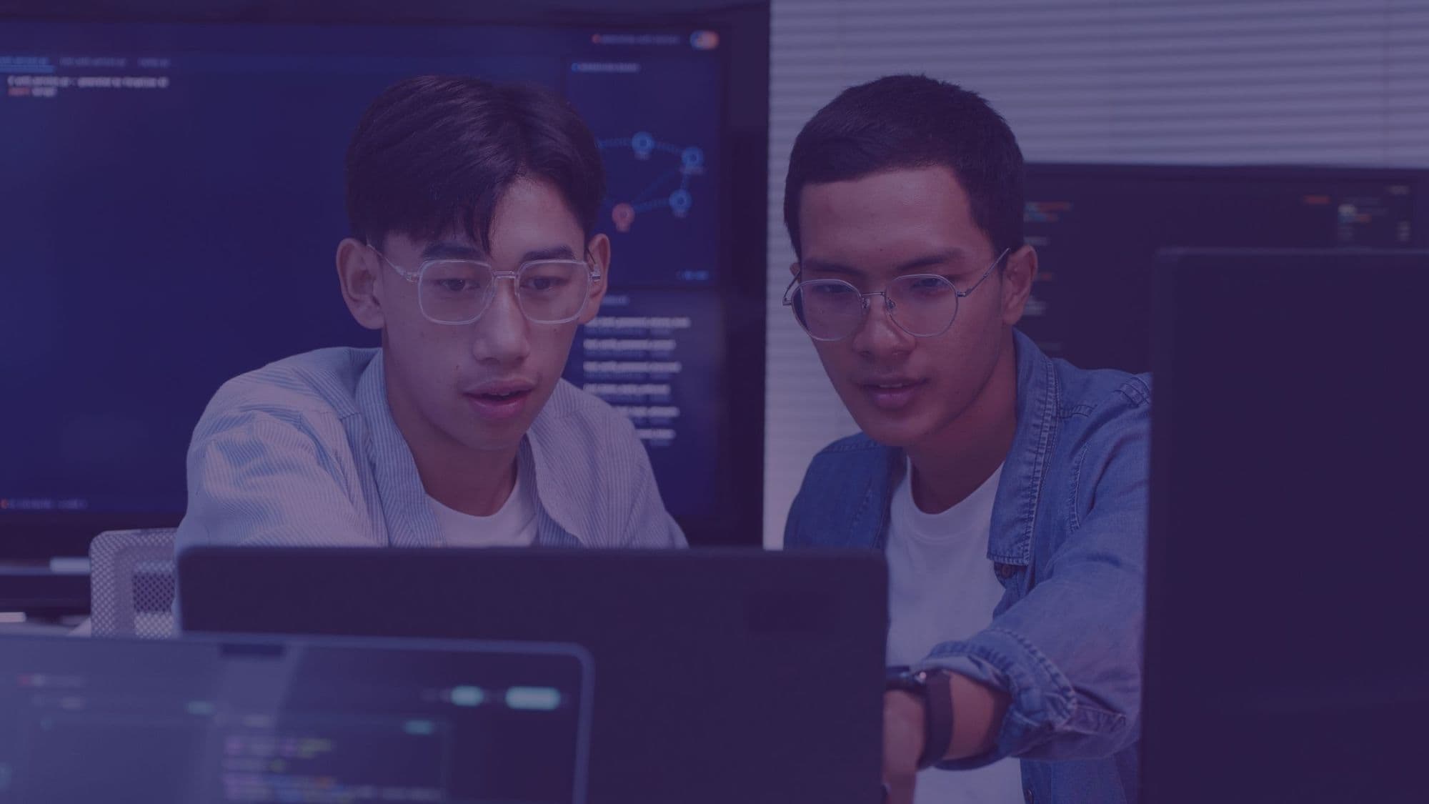 Two economics professionals analysing data on multiple screens