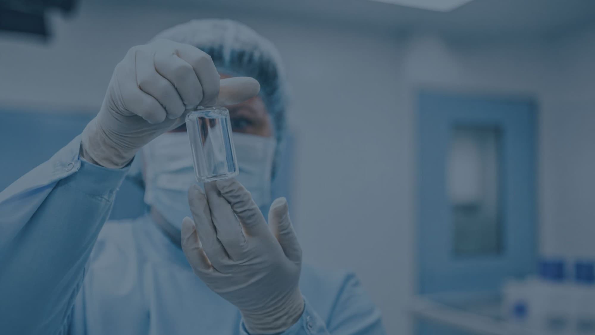 A pharmaceutical researcher examining a vial in a cleanroom laboratory